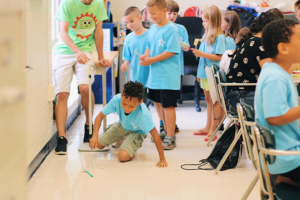 67073455_2712082409018086_4248263520975585280_n US space camp: a young boy tests a project while other kids watch.